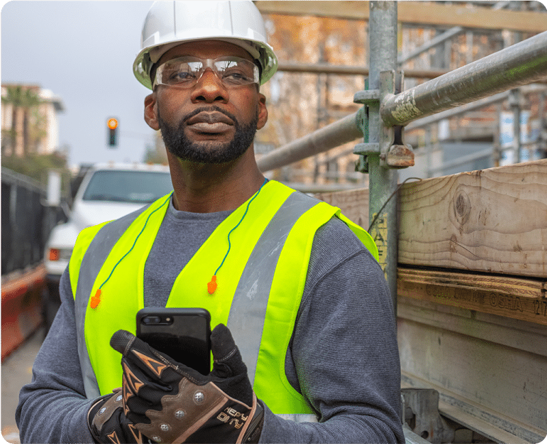 Construction worker looks up from his phone