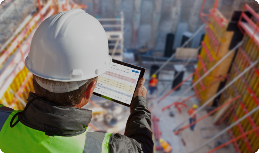 Construction worker with tablet looks at jobsite from above