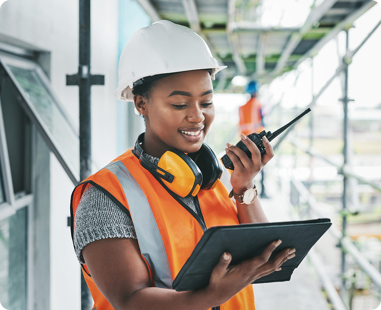 Construction worker speaking on radio and holding a tablet