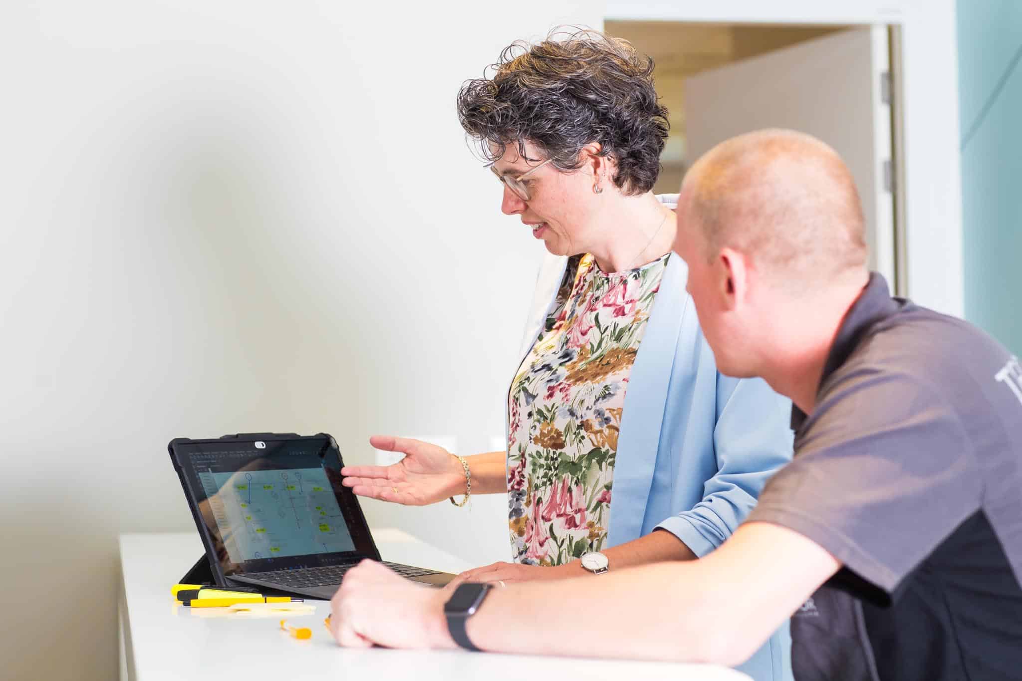 Two people examine a laptop