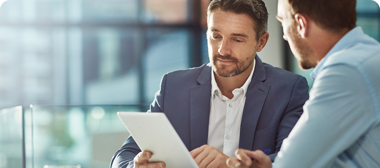 Two men in professional attire look at tablet