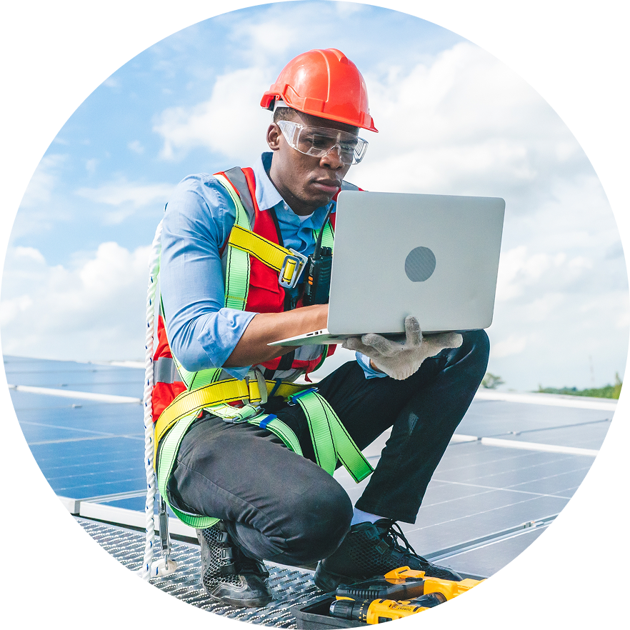 Construction worker in safety gear crouched with laptop