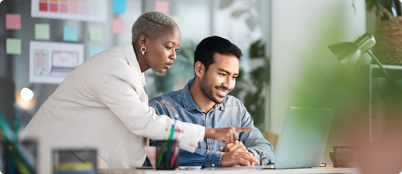  Two coworkers look at laptop together 