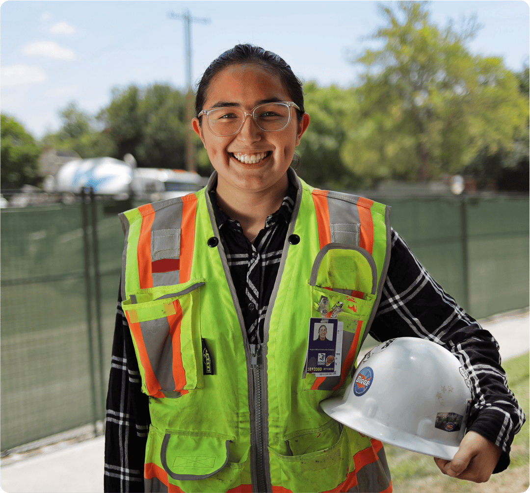 Trabajador de la construcción (arquitectura, ingeniería, construcción) en PPE sosteniendo un casco y sonriendo