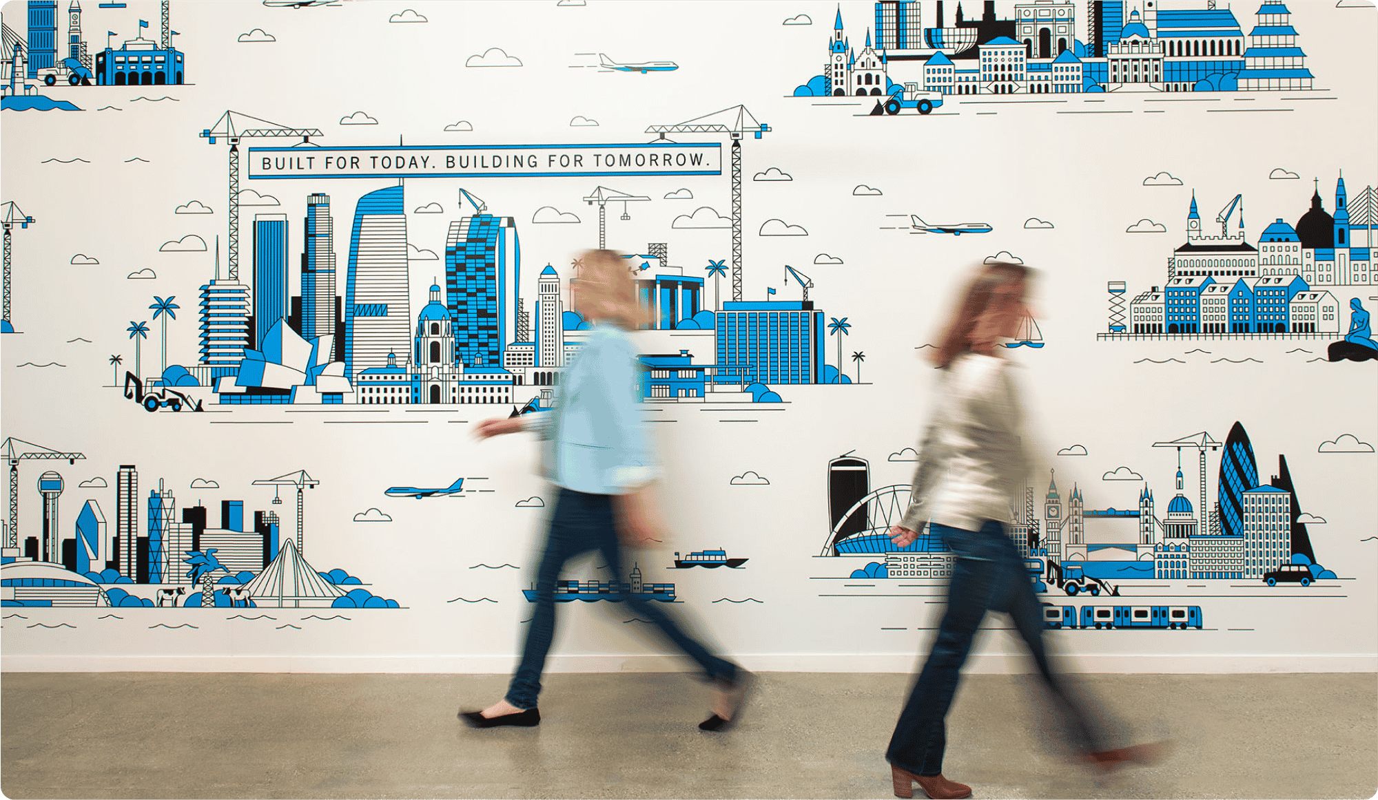 employés Bluebeam marchant devant la fresque murale des bureaux de Bluebeam « Built for today. Building for tomorrow. »