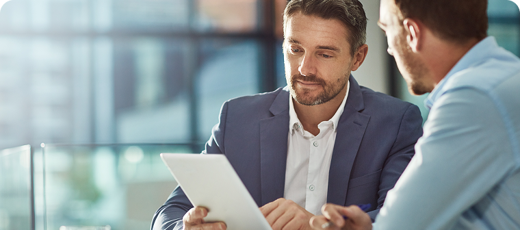 Two men in professional attire look at tablet
