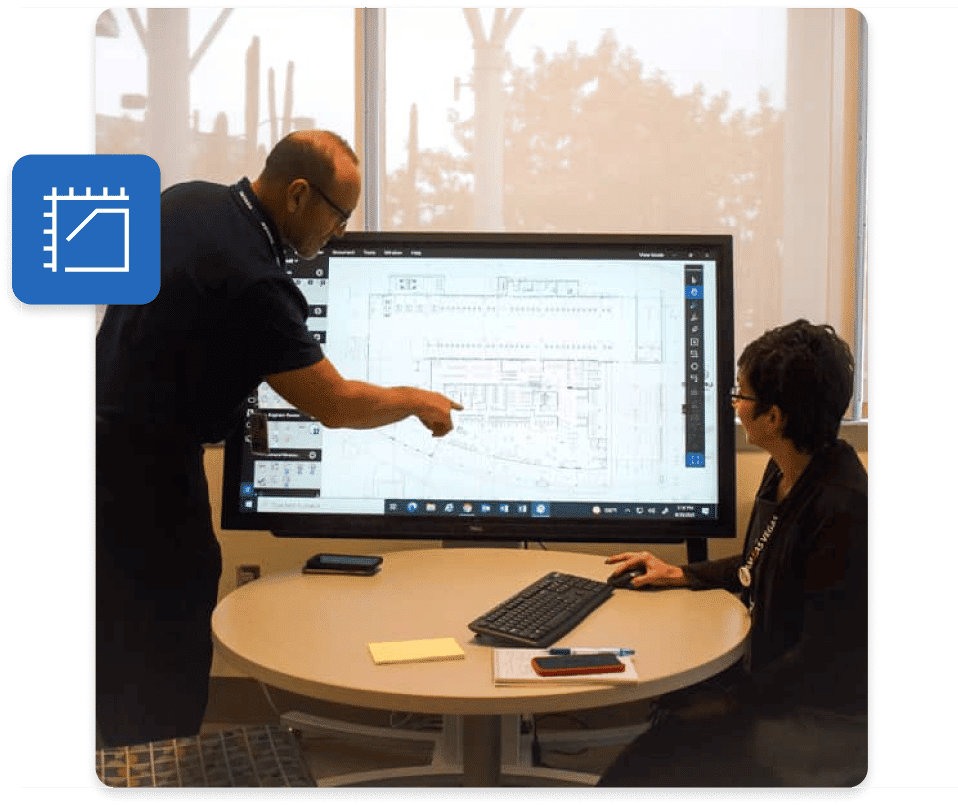 Människor arbetar på ett kontor med stor skärm och använder Bluebeams byggprogramvara för offentlig sektor