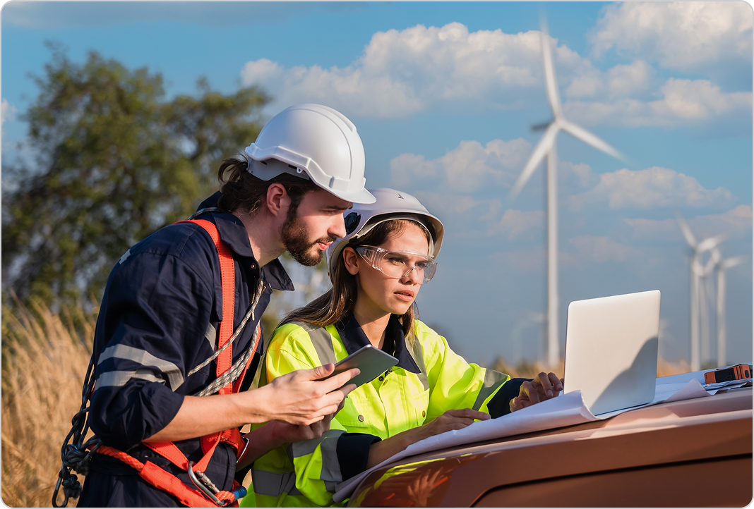 Two construction workers look at laptop on top of truck