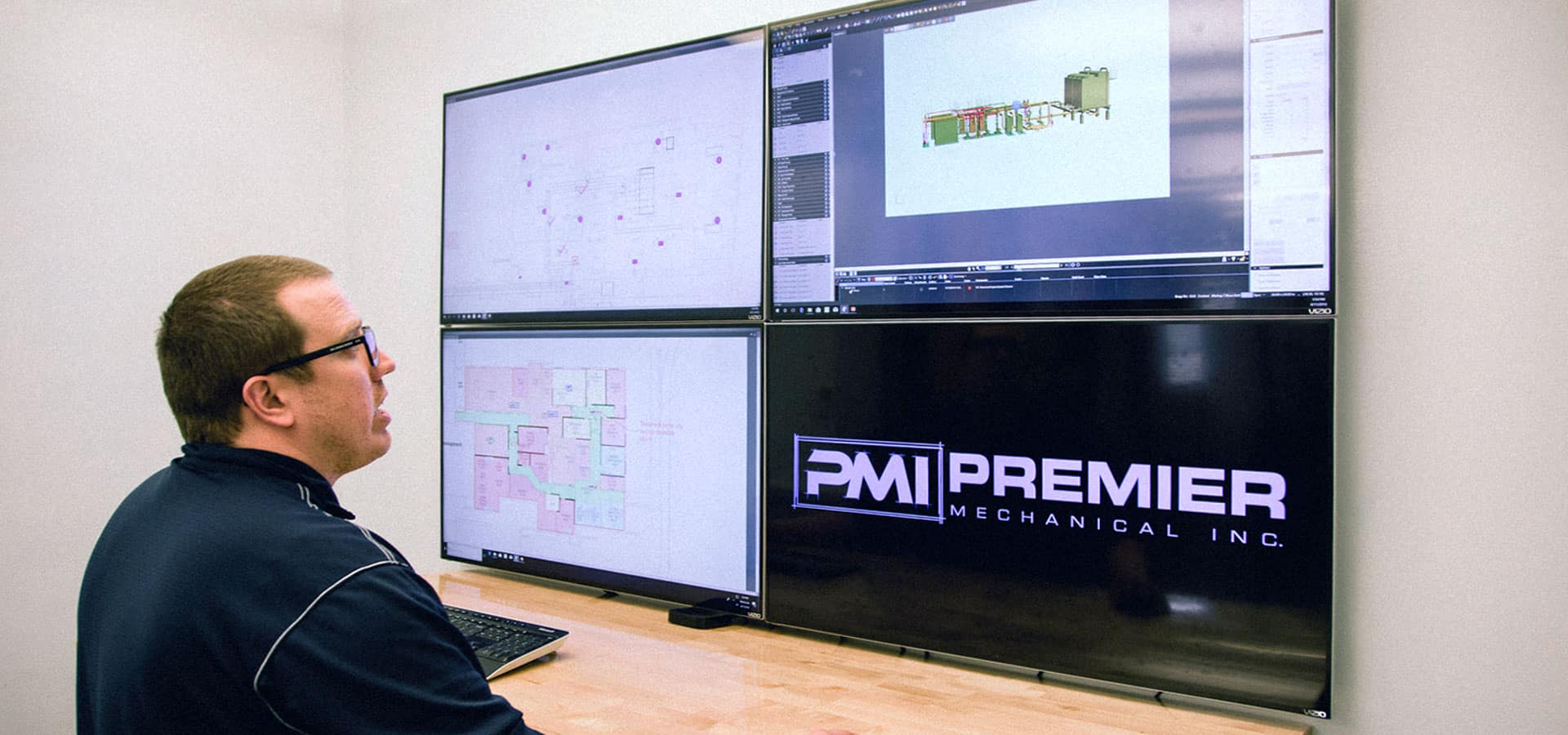 man viewing screens with construction drawings for Premier Mechanical