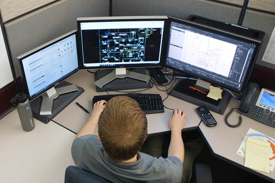 man working on computer screens with digital construction drawings