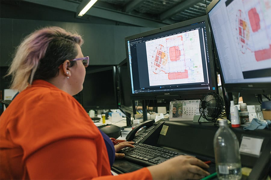 woman viewing construction drawings on computer in office