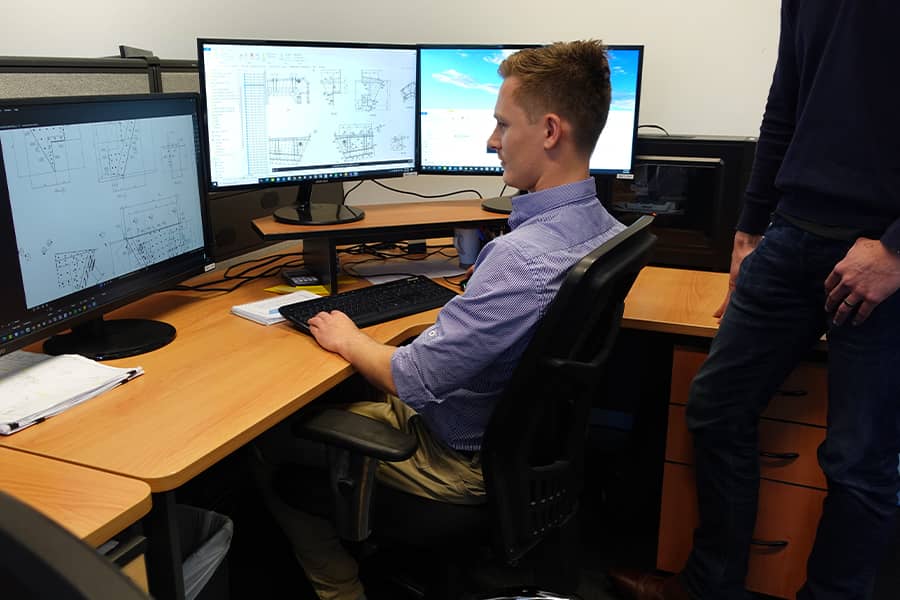 man working on construction drawings in office on computer