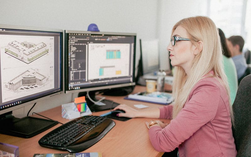 woman in office working on computer with construction files