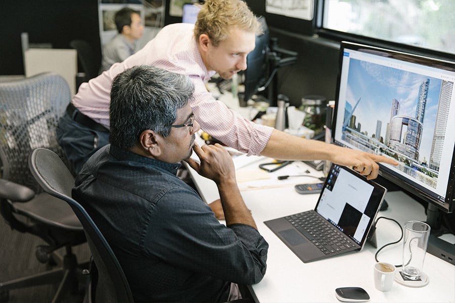 two men viewing construction rendering on computer in office