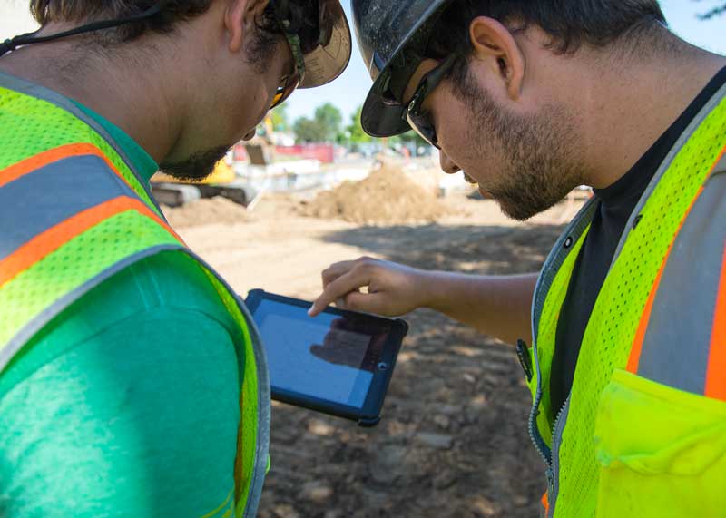 two men in construction PPE viewing a tablet with a drawing