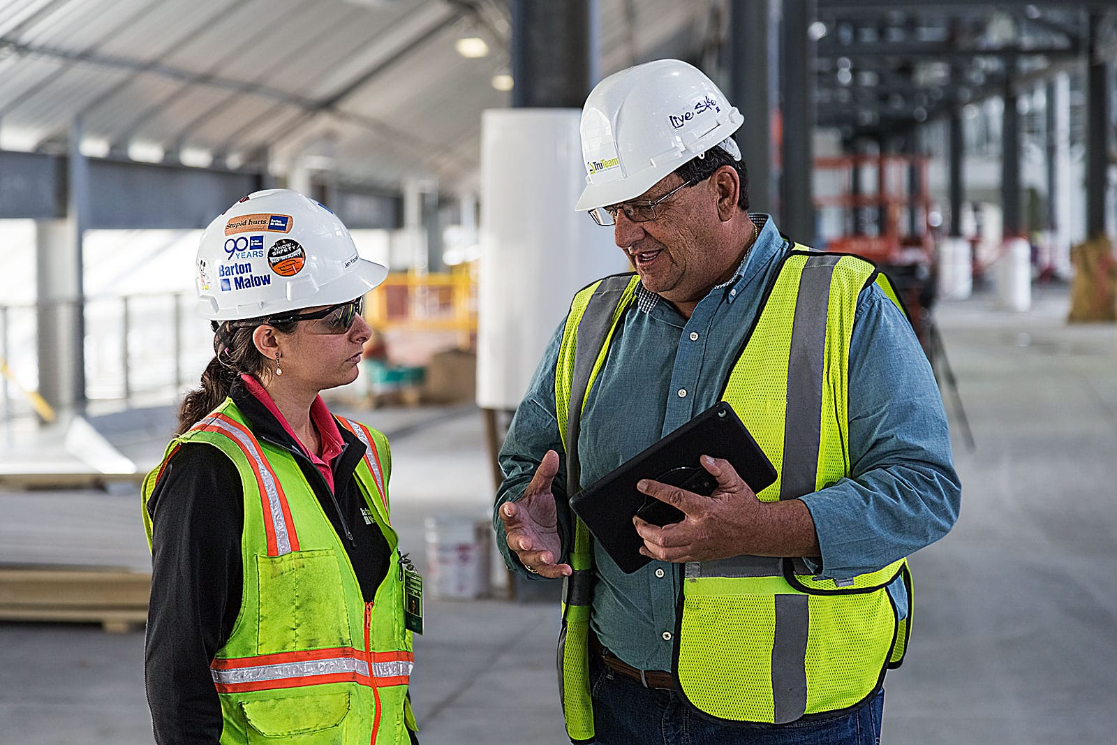 two people in construction PPE talking on job site