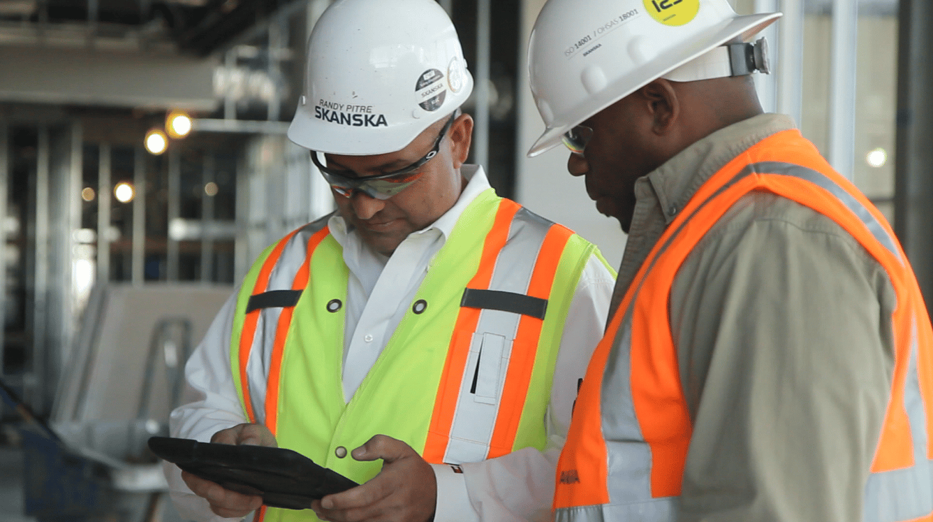 two men with Skanska helmets looking at tablet