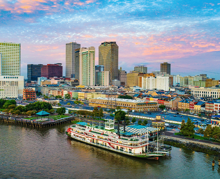 A picture of the New Orleans skyline, with a river and boat in the foreground