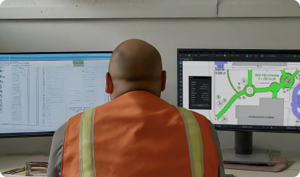 Worker in safety vest looks at monitors with Revu and a spreadsheet