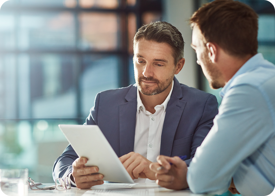  Two men in suits conversing, one looks at tablet 
