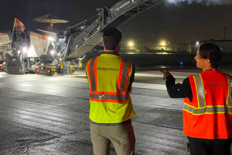 Two Kimley-Horn team members oversee nighttime airport construction using milling equipment