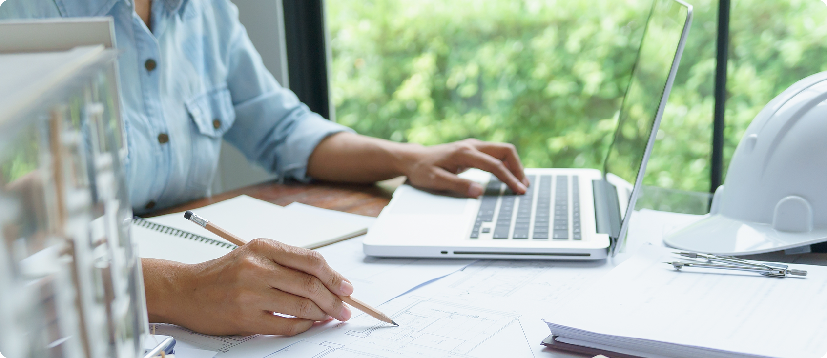  Person in button-up works on laptop and writes on paper 