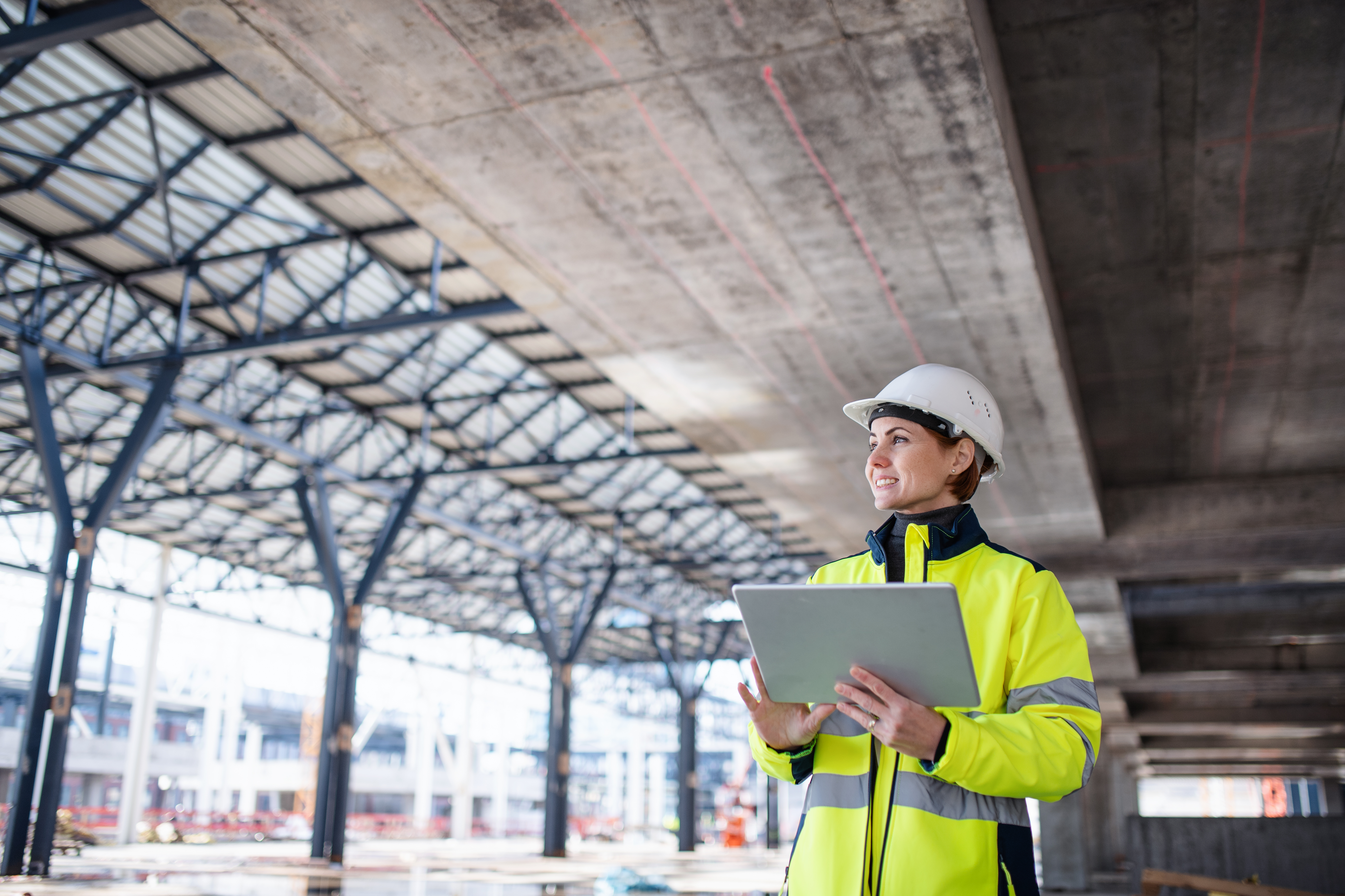 Engineer in safety gear surveys jobsite with laptop