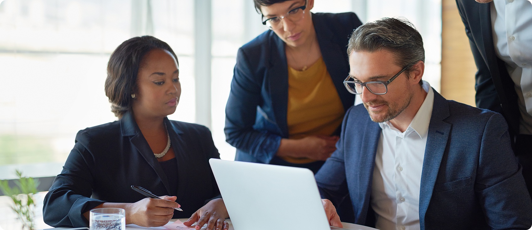  Group of people in professional attire look at laptop together 