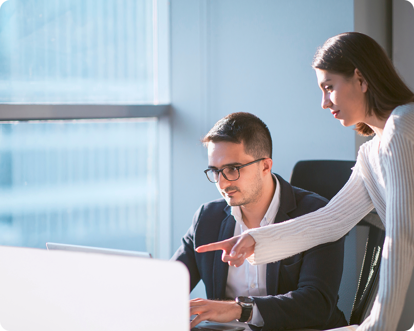 An office worker points something out on colleague's laptop