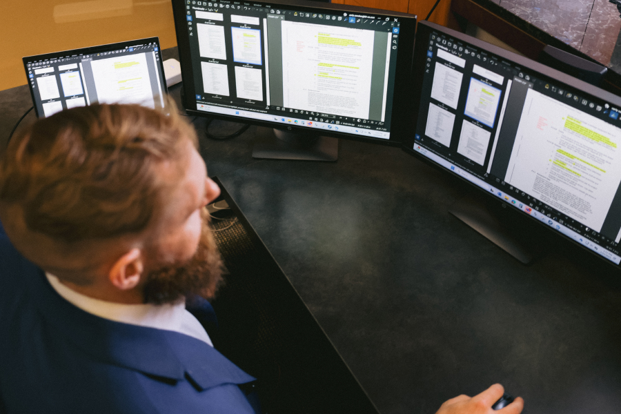 Brian at a triple-monitor setup reviewing PDFs in Bluebeam